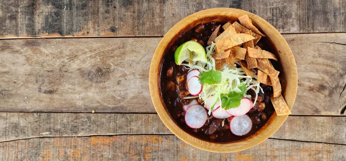 Pozole Rojo in a wooden bowl with wood background